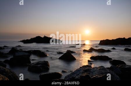 Blick auf die Sonne oder die Sternensonne über den Felsen mit Sonnenuntergang am Hintergrund im atlantik, Punta Ballena, Maldonado, Uruguay Stockfoto