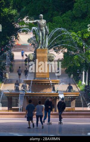 Der Archibald Fountain befindet sich im Hyde Park in Sydney, Australien. Benannt ist es nach J.F. Archibald, der Gelder vermachte, um sie bauen zu lassen. Archibald legte fest, dass es von einem französischen Künstler aufgrund seiner großen Liebe zur französischen Kultur entworfen werden muss und um der Vereinigung Australiens und Frankreichs in WW1 zu gedenken. Er wünschte, Sydney strebe nach Pariser Civic Design und Ornamentik. Als Künstler ausgewählt wurde François-Léon Sicard, der es 1926 in Paris fertigstellte, aber nie sah, wie die Skulptur in Sydney aufgestellt wurde, wo sie im März 1932 vom Oberbürgermeister von Sydney, Samuel Walder, enthüllt wurde. Stockfoto