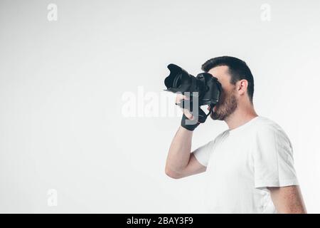 Seitenansicht des Fotografen isoliert über weißem Hintergrund aufnehmen von Bildern oder Fotos mit speziellen Geräten. Allein im Studio. Stockfoto