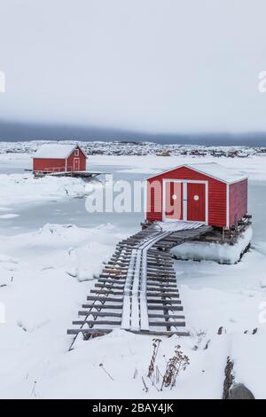 Red Stages und eine Rampe aus Holzwagen am schneebedeckten Ufer von Joe Batt's Arm auf Fogo Island in Neufundland, Kanada [keine Freigabe für Immobilien; zur Bearbeitung verfügbar Stockfoto