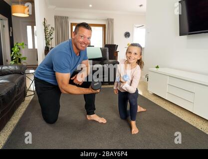 COVID-19-Abschaltung. Vater und Tochter in Quarantäne trainieren zusammen mit Hanteln. Vorteile der körperlichen Aktivität während des Sperrens. Bleiben Sie zu Hause, Stockfoto