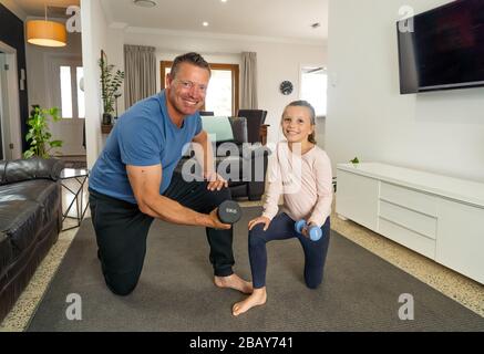 COVID-19-Abschaltung. Vater und Tochter in Quarantäne trainieren zusammen mit Hanteln. Vorteile der körperlichen Aktivität während des Sperrens. Bleiben Sie zu Hause, Stockfoto