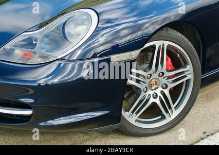 Silbernes fünfspeichiges Leichtmetallrad vor dunkelblauem Porsche Boxster Stockfoto