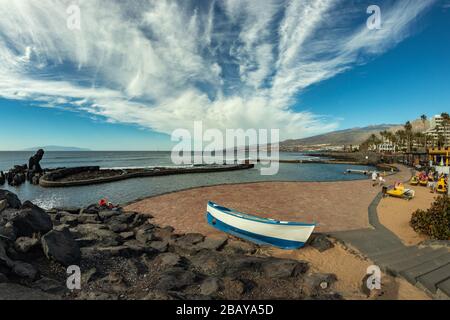 Küste in Las Americas, auf Teneras, Spanien. Heller Farbhimmel mit schönen Wolken. Fischerboot im Vordergrund. Blick auf die Insel La Gomera. Stockfoto