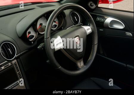 Modernes, schwarzes Autolenkrad, das in einen roten Porsche Boxster eingebaut ist Stockfoto