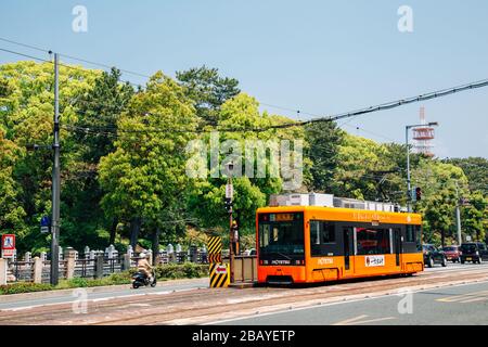 Matsuyama, Japan - 21. April 2019: Straßenbahn der Stadt mit grünen Bäumen Stockfoto