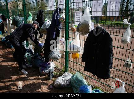 München, Deutschland. März 2020. Björn Boueke ordnet die Sachspenden an, die Bürger an einem sogenannten Geschenkzaun an den Zaun eines Fußballfeldes für Obdachlose gehangen haben. Obdachlose sind besonders von der Corona-Pandemie betroffen. Das Hilfesystem zerfällt zunehmend, gleichzeitig müssen die oft immungeschwächten Menschen vor allem eine Infektion fürchten. Credit: Bernd Thissen / dpa / Alamy Live News Stockfoto