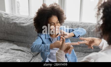 Afrikanisches kleines Mädchen mit Zeichensprache kommuniziert mit der Mutter Stockfoto