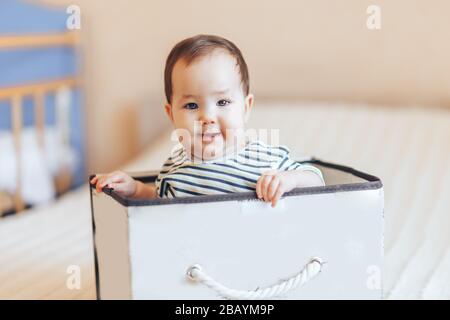 Hübsches Baby Kleinkind Junge oder Mädchen, das in einer Kiste in der Wohnung sitzt Stockfoto