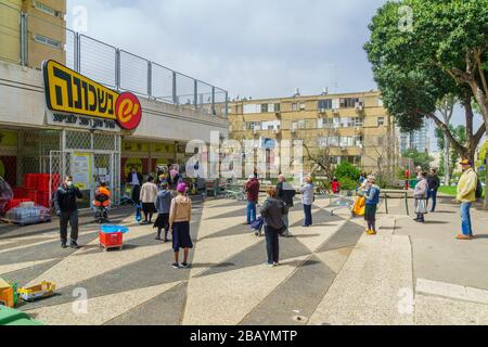 Haifa, Israel - 24. März 2020: Die Menschen folgen den Regeln der sozialen Distanzierung, während sie außerhalb eines Supermarktes warten (wegen der Beschränkungen der Kundenzahlen). Coron Stockfoto