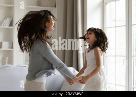 Junge Mutter und kleine Tochter tanzen zuhause zusammen Stockfoto