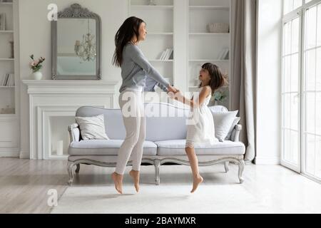 Überglücklich tanzten junge Mutter und kleine Tochter zusammen Stockfoto