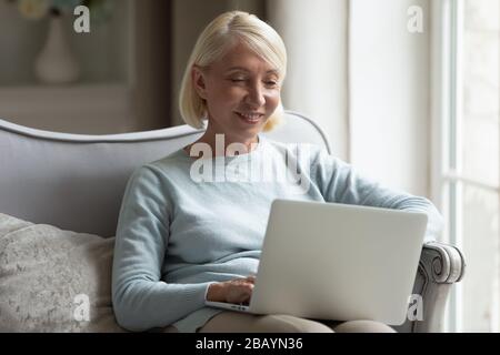 Glückliche Seniorin entspannen mit Laptop zu Hause Stockfoto