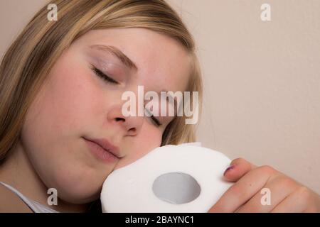 Mädchen umarmt während der Pandemie eine einzelne Rolle Toilettenpapier Stockfoto