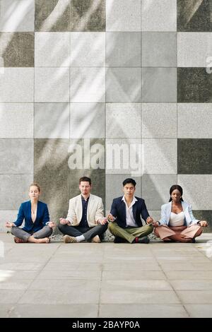 Erfolgreiches multiethnisches Business-Team, das gemeinsam die Meditation praktiziert Stockfoto