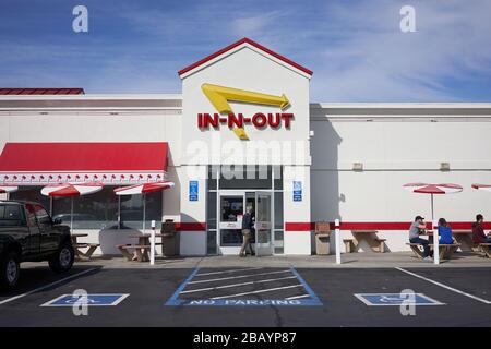 Ein Mann betritt ein Redwood City-Lokal in der Fast-Food-Restaurantkette in-N-Out. Ein paar Restaurantbesucher wählen Outdoor-Sitzplätze. Stockfoto