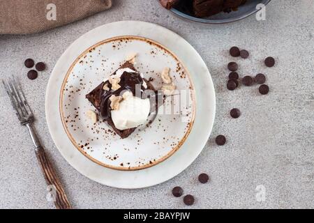 Hausgemachte Brownie mit einer Schaufel Vanilleeis, Schokoladensoße und Nüssen Stockfoto