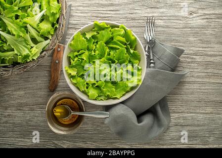 Gesunder grüner Salat auf Holztisch. Frisch gepflückt mit jungen grünen Blättern Stockfoto