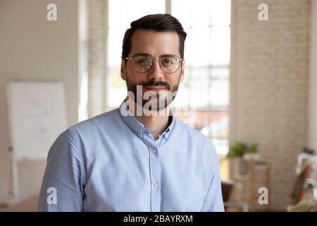 Headshot Portrait erfolgreicher Geschäftsmann, der im Büro steht und sich für die Kamera posiert Stockfoto
