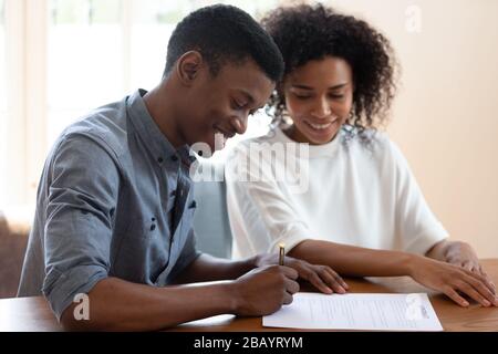 Zufriedenes afrikanisches Ehepaar mit ethnischer Zugehörigkeit, das einen Mietvertrag unterzeichnet Stockfoto