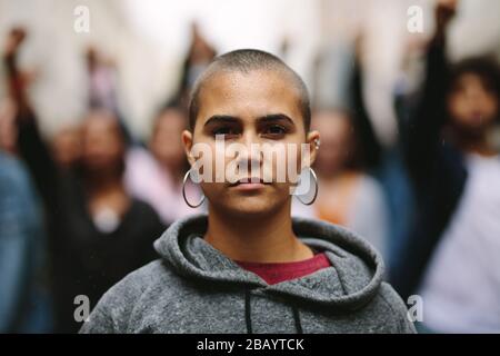 Woman protestor mit einer Gruppe von Menschen im Hintergrund auf der Straße der Stadt. Aktivisten protestieren lautlos in der Stadt. Stockfoto