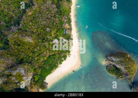 Luftdronblick auf Langschwänzboote an einem schönen tropischen Strand, umgeben von üppigem grünen Dschungel (Phra Nang, Railay) Stockfoto