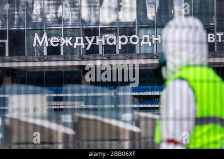 Moskau, Russland. Am 21. März 2020 kontrolliert ein Beamter der Verkehrskontrollbehörde den Bus bei einem Ausbruch des COVID-19-Coronavirus im Internationalen Busbahnhof Nord in der Moskauer Stadt, Russland. Das Banner lautet "The International Bus Station". Stockfoto