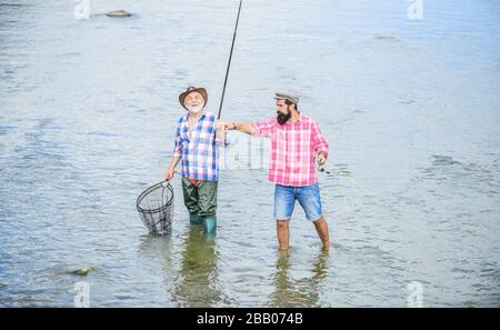 Arbeiten Sie im Team. Landurlaub. Hobby. Wilde Natur. Zwei glückliche Fischer mit Angelrute und Netz. Camping am Ufer des Sees, Vater und Sohn angeln. Wildern. Großes Spiel Angeln. Freundschaft. Stockfoto