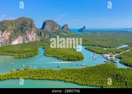 Luftdronblick auf kleine Boote in einem Mangrovenwald, umgeben von großen Kalkfelsen (Phang Nga Bay) Stockfoto