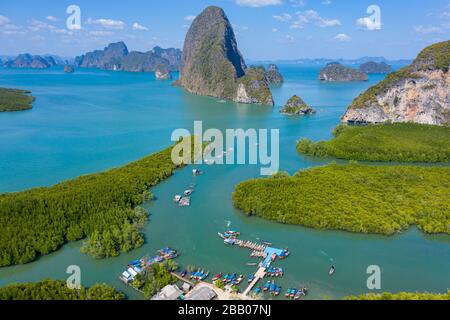 Luftdronblick auf kleine Touristenboote in einem Mangrovenwald, der mit einer Bucht mit hoch aufragenden Kalkinseln verbunden ist (Phangnga Bay, Thailand) Stockfoto