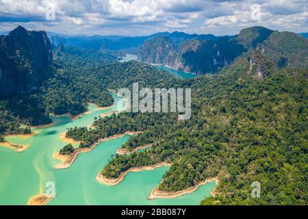 Luftdronblick auf tropischen Regenwald und kleine Inseln auf einem riesigen See, der von Kalkfelsen umgeben ist (Cheow LAN, Khao Sok, Thailand) Stockfoto