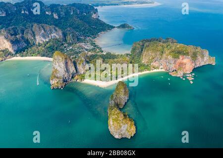 Luftdronblick auf einen schönen tropischen Strand, hoch aufragende Klippen und grünen Dschungel auf einer isolierten Halbinsel. (Railay Beach, Krabi) Stockfoto