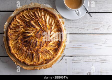 Hausgebackene apfelkuchen auf einem weißen Holztisch mit einer Tasse Kaffee auf der Seite. Draufsicht. Stockfoto