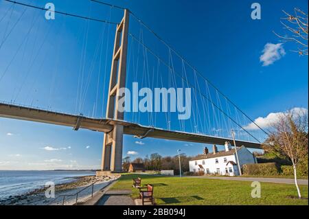 Große Hängebrücke, die an einem klaren Tag mit blauem Himmel und Wolken eine breite Flussmünde überspannt Stockfoto