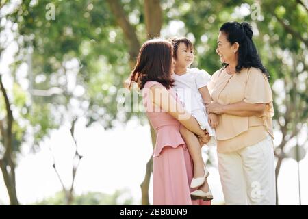 Junge Frau und ihre kleine Tochter besuchen ihre ältere Mutter und verbringen gemeinsam Zeit im Park Stockfoto
