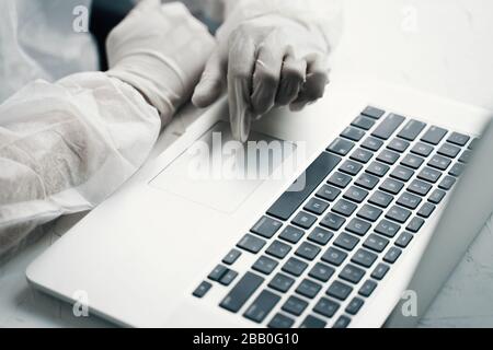 Bio Hazard man mit Laptop. Hände in Handschuhen mit Laptop. Stockfoto