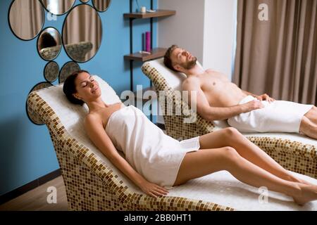 Junges Paar, das auf den Tepidariumbetten im Spa liegt Stockfoto