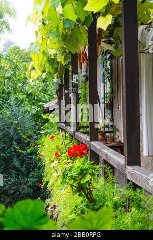 Ein Balkon in einem historischen Bauernhaus in Trient, Italien. Der Balkon öffnet das obere Stockwerk. Hier sind Blumenkannen und viele Gegenstände. Stockfoto