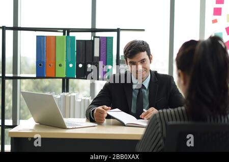 Junge Arbeitgeber in schwarzen Anzügen bewerten Stellenbewerber, indem sie Fragen zur Marketingstrategie stellen. Stockfoto