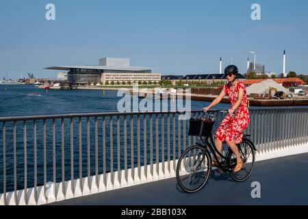 Dänin fährt mit dem Fahrrad auf einer Brücke in der Nähe der Kopenhagener Oper, Kopenhagen, Dänemark, Europa Stockfoto