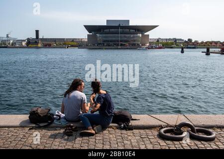 Die Menschen genießen die Sonne am Kai gegenüber der Kopenhagener Oper in Kopenhagen, Dänemark, Europa Stockfoto