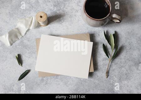 Mediterrane Frühstückszeit Stillleben .Moody feminine Hochzeitstiererei Mock-up Szene. Leere Grußkarte, Tasse Kaffee und grüne olivgrüne Blätter, Zweig Stockfoto