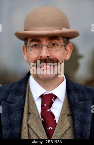 Ein Gentleman hat einen Schnurrbart, während er während des Gentleman's Day auf der Sandown Racecourse klassische Kleidung trägt Stockfoto