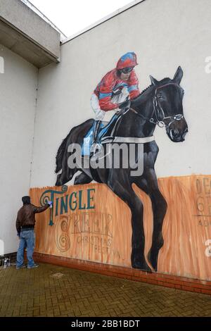 Der Graffiti-Künstler Olivier Roubieu wendet den letzten Schliff auf sein Wandbild an, das Sandown's Tingle Creek Christmas Festival während des Gentleman's Day wirbt Stockfoto