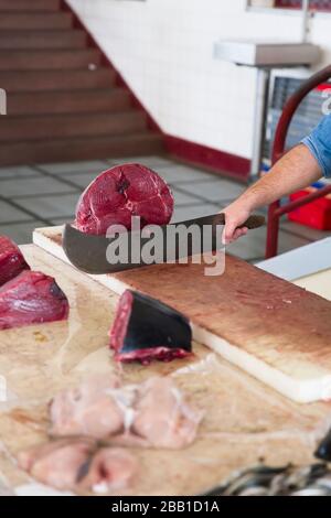 FUNCHAL, PORTUGAL - 15. FEBRUAR 2020: Unidentifizierter Mann schneidet Thunfisch Mercado dos Lavradores (Bauernmarkt) in Funchal auf der Insel Madeira, Portugal. M Stockfoto