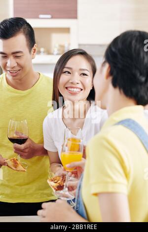 Hübsche junge Asiatin, die mit ihren Freunden eine Party im Haus macht und einen Cocktail mit Zitrusfrüchten trinkt Stockfoto