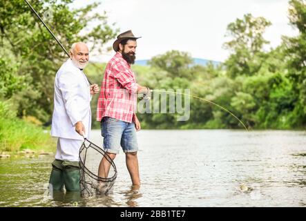 Geht zum Fischfang. Hobby des Geschäftsmannes. Pensionsfischerei. Vater im Ruhestand und Sohn im Alter. Freunde Männer mit Angelrute und Netz. Glückliche Fischer. Guter Gewinn. Abenteuer beim Fliegenfischen. Stockfoto