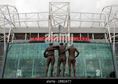 Zu sehen ist eine allgemeine Ansicht von Old Trafford, die United Trinity Statue der ehemaligen Spieler George Best, Denis Law und Bobby Charlton Stockfoto