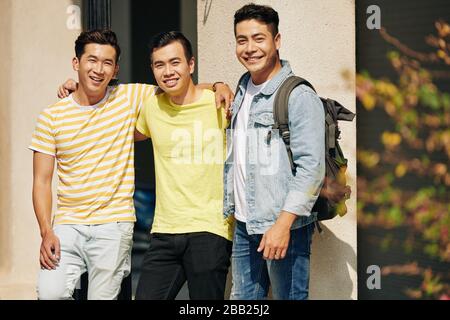 Eine Gruppe fröhlicher asiatischer Studenten, die die Kamera umarmen und lächeln Stockfoto
