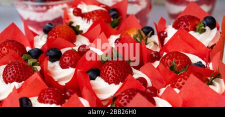 Dessert mit Blaubeeren und Erdbeeren in Tassen mit Sahne. Köstlicher Beerenhintergrund Stockfoto